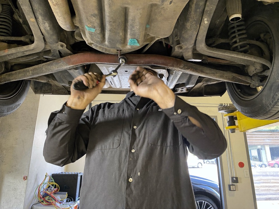 A technician working under a car raised on the lift.